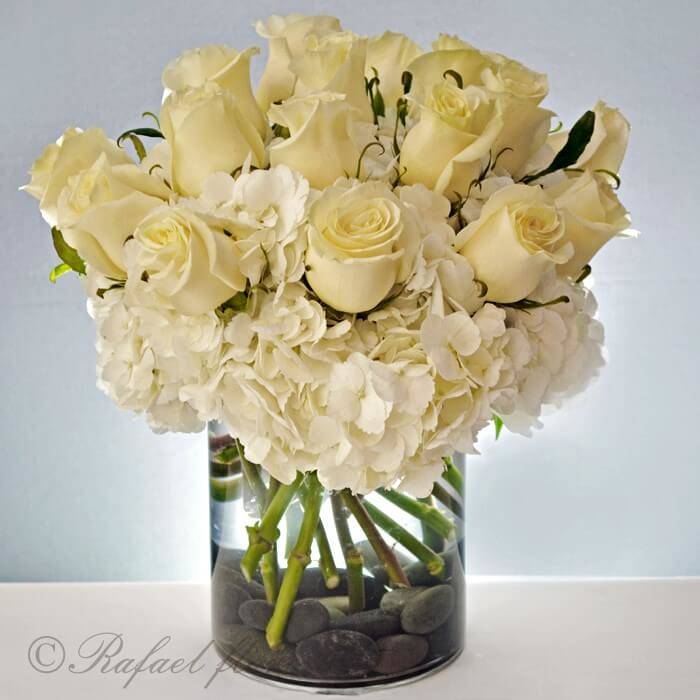 Beautiful floral design of white hydrangeas and roses in a clear glass vase